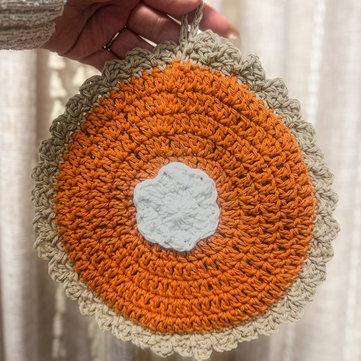 15 Friendsgiving Gift Ideas for Hosts and Guests 6 Crocheted pumpkin pot holder with orange, white, and beige yarn colors.