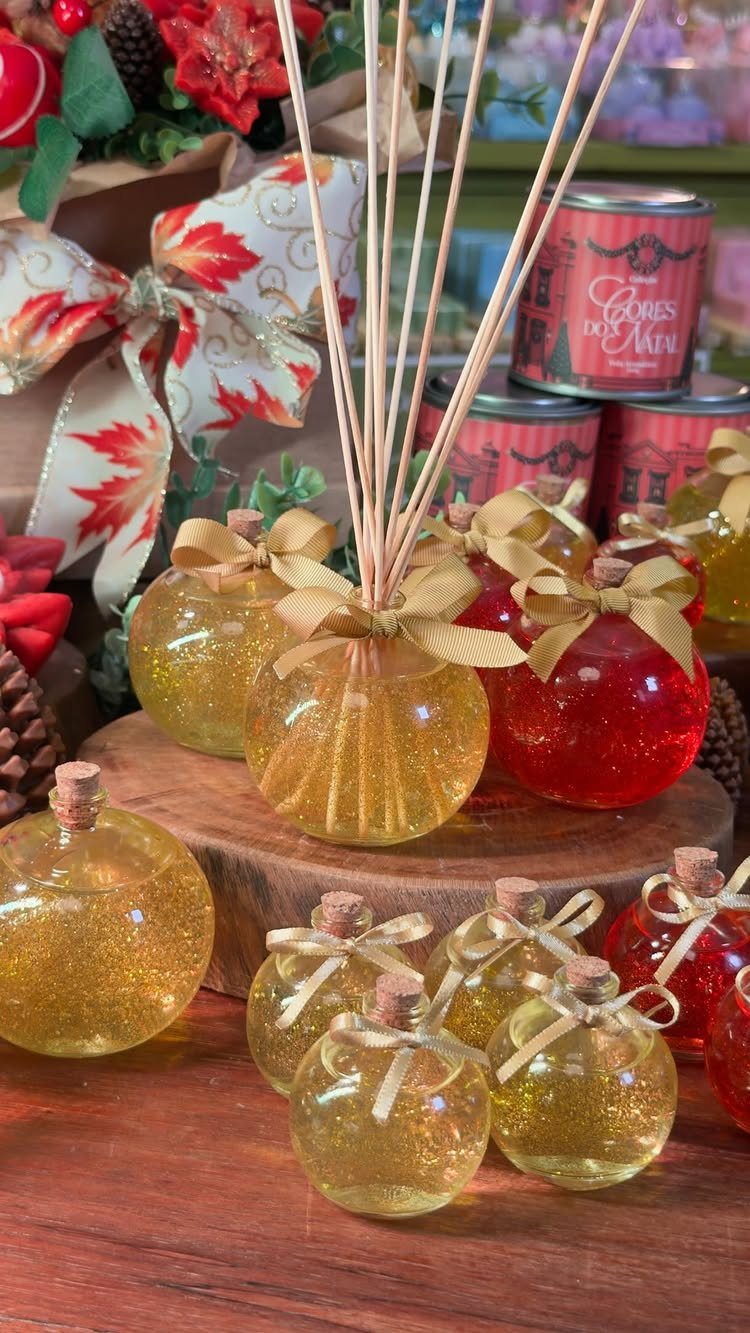 15 Friendsgiving Gift Ideas for Hosts and Guests 1 Round glass reed diffuser bottles with gold glitter and bows on wooden surface.