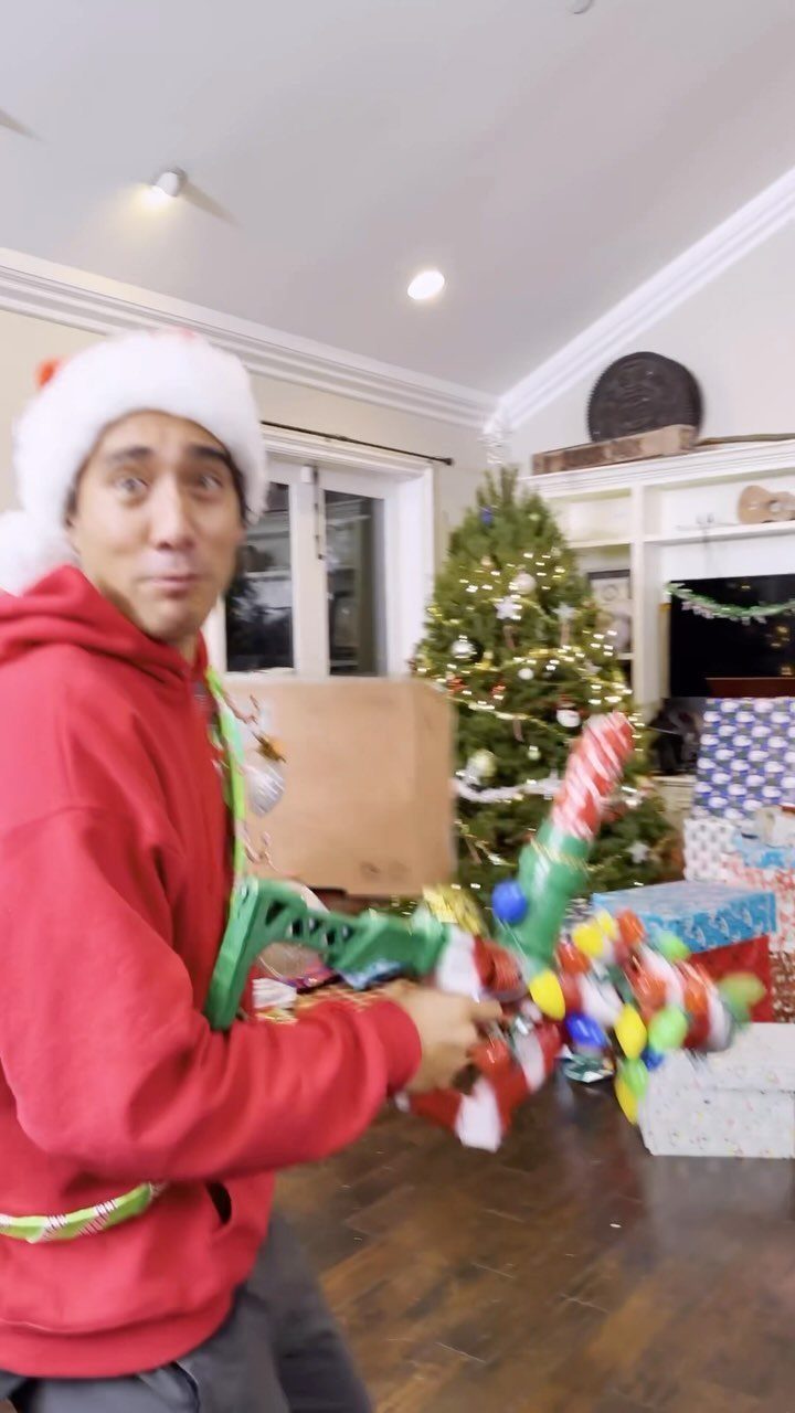 9 Funny Christmas Gift Wrapping Ideas Your Family Will Love 4 Man in Santa hat holding a gift wrapped like a green rifle