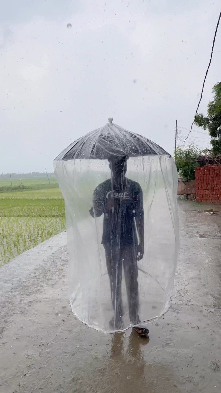 13 Funny Gag Gift Ideas for Birthdays and Office Parties 6 Person standing inside a full-length clear plastic umbrella on a rainy day.