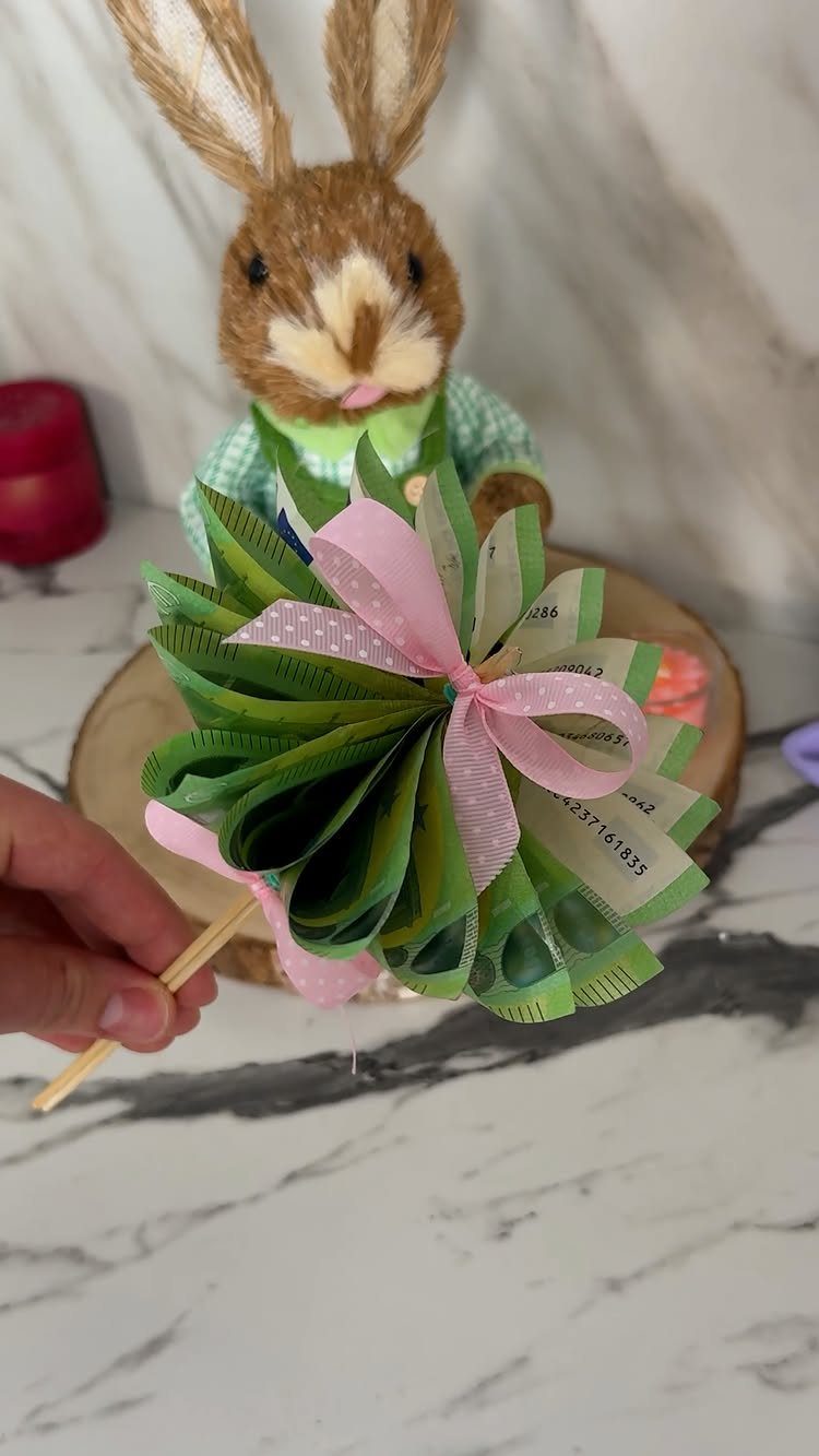 9 Funny Money Gift Ideas to Make Cash Feel Like a Gift 3 Folded green banknotes shaped into a flower with a pink polka-dot ribbon.