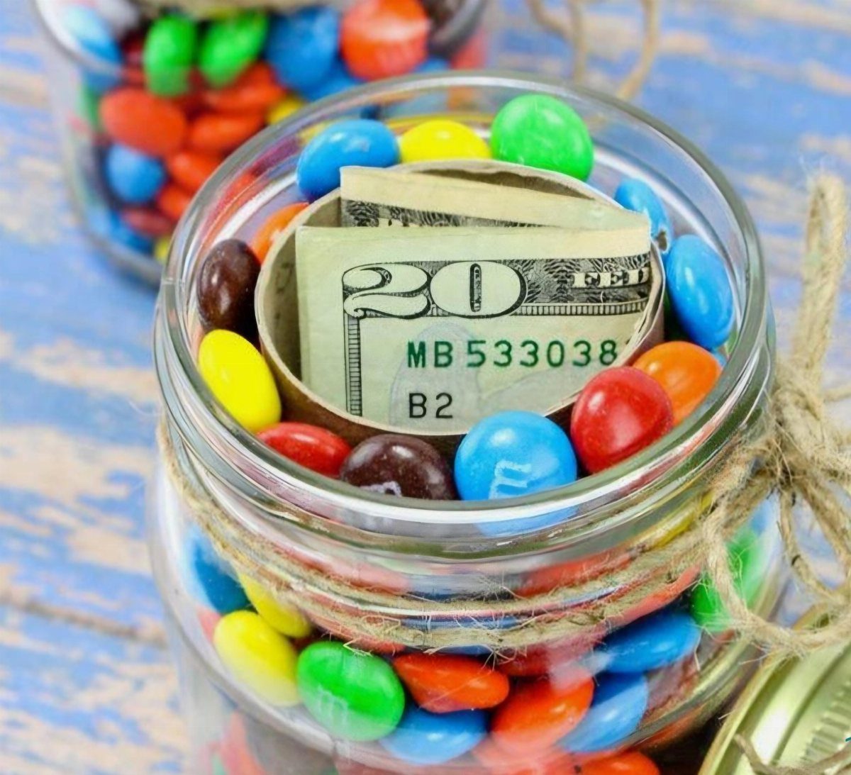 9 Funny Money Gift Ideas to Make Cash Feel Like a Gift 8 Glass jar filled with colorful candies containing a cardboard tube with a twenty-dollar bill.