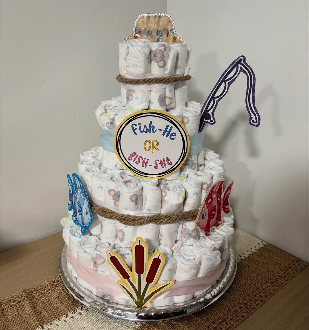 5 Gender Reveal Gifts for Parents-to-Be and Baby 1 Three-tiered diaper cake decorated with fish cutouts and a gender reveal sign.