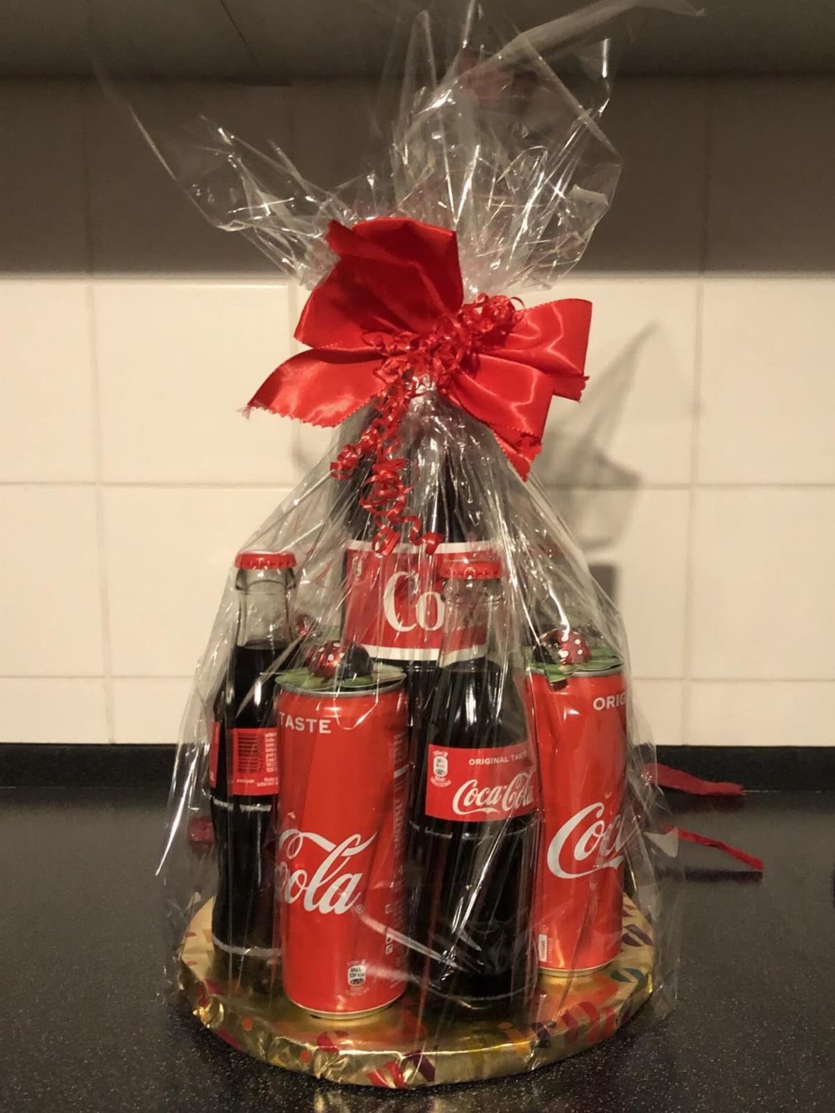 15 Gift Basket Alternative Ideas for Any Occasion 8 Coca-Cola bottles and cans wrapped in cellophane with a red bow.