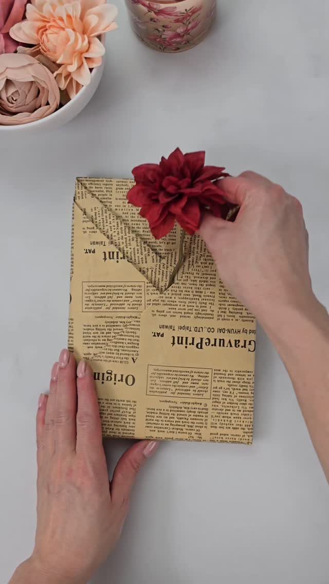 15 Gift Basket Alternative Ideas for Any Occasion 2 Gift wrapped in newspaper print paper with a gold string and red flower.