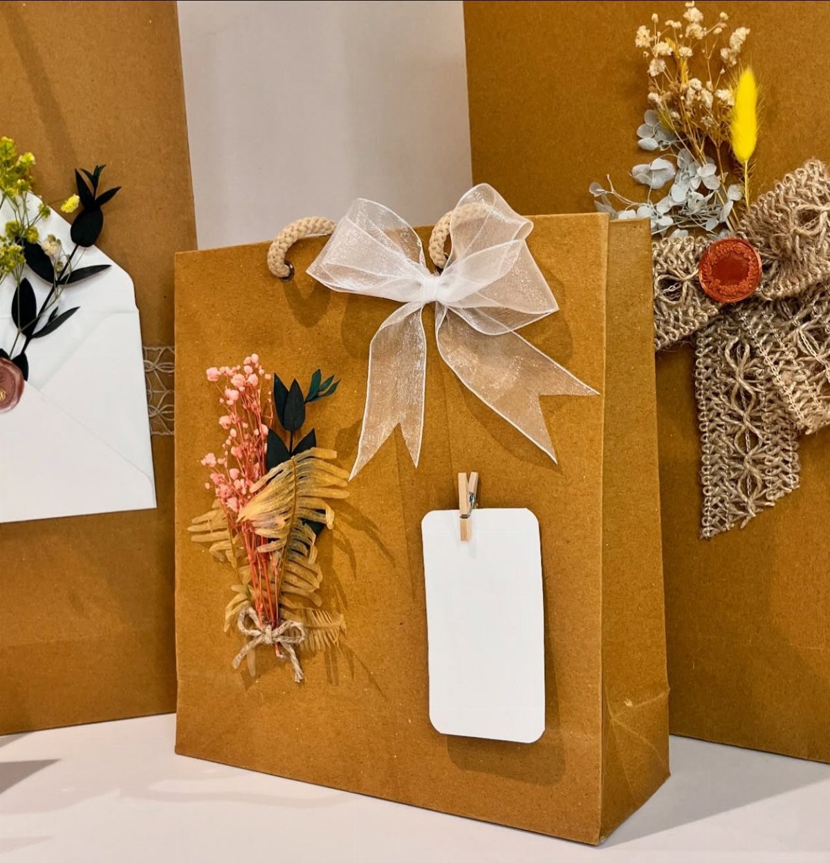 15 Gift Basket Alternative Ideas for Any Occasion 4 Brown paper gift bag decorated with a white bow and dried flowers.