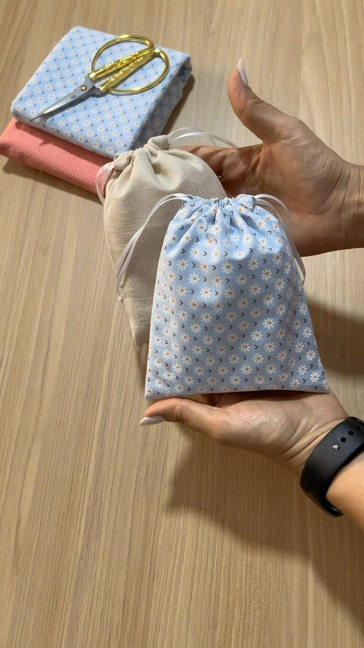 15 Gift Basket Alternative Ideas for Any Occasion 3 Two small fabric drawstring pouches, one floral and one beige, held by hands.