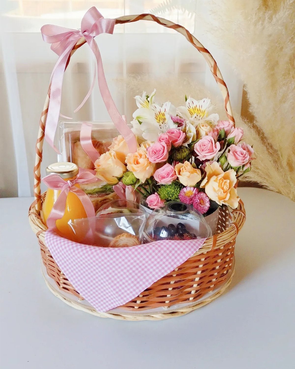Gift Basket Design: 18 Ideas for Every Occasion 9 Woven gift basket with orange juice, pastries, and a bouquet of pink roses.