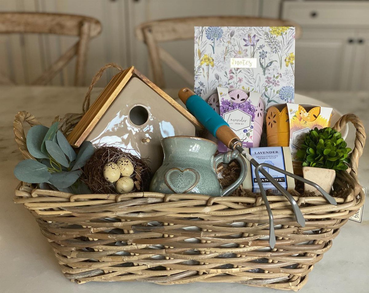 Gift Basket Design: 18 Ideas for Every Occasion 8 Woven gift basket containing a birdhouse, hand rake, heart mug, and floral stationery.