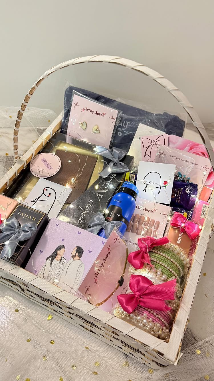 Gift Basket for Couple Ideas: 5 Picks to Give Together 4 White woven gift basket containing jewelry, pink bows, and a couple's illustration card.