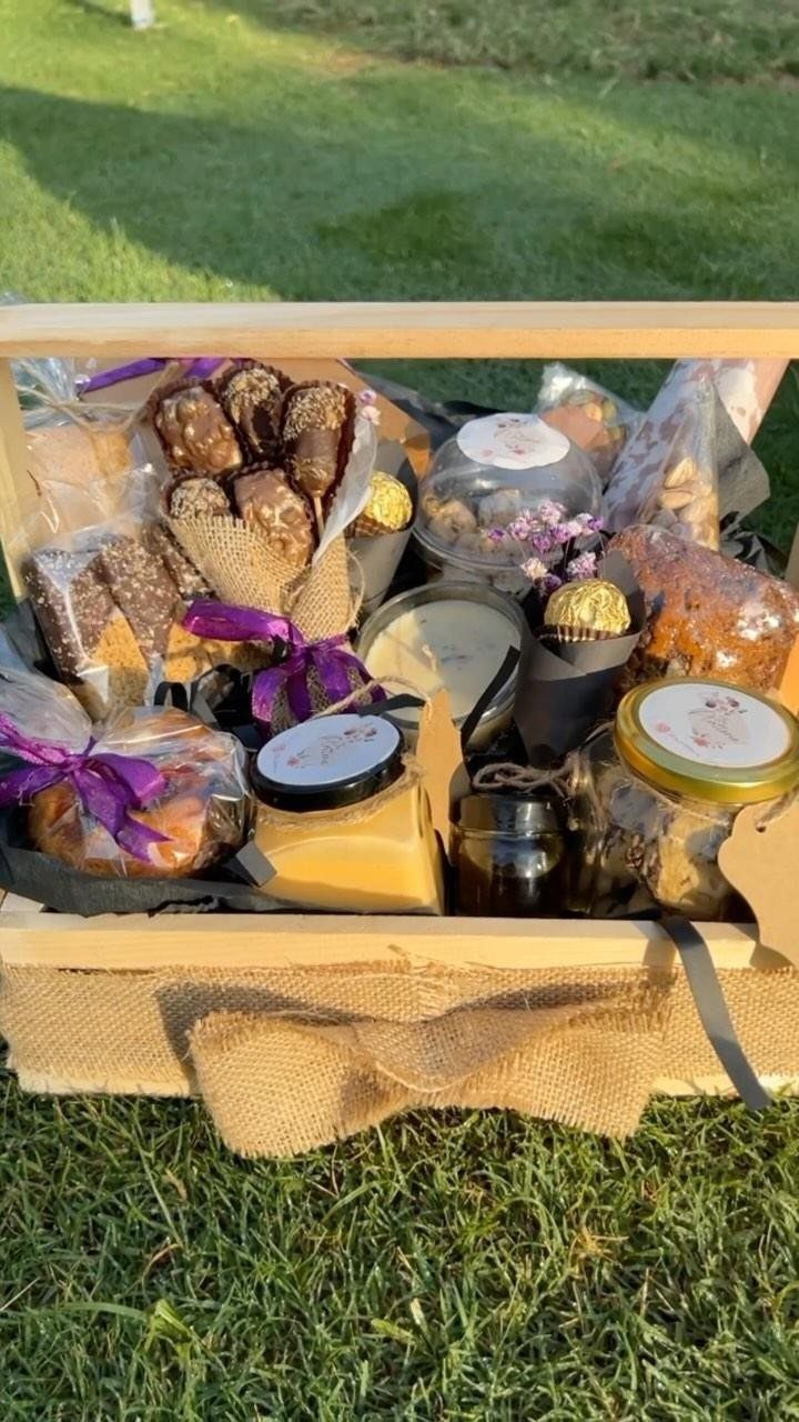 Gift Basket for Couple Ideas: 5 Picks to Give Together 2 Wooden gift crate filled with gourmet snacks, jars, and sweets on green grass.