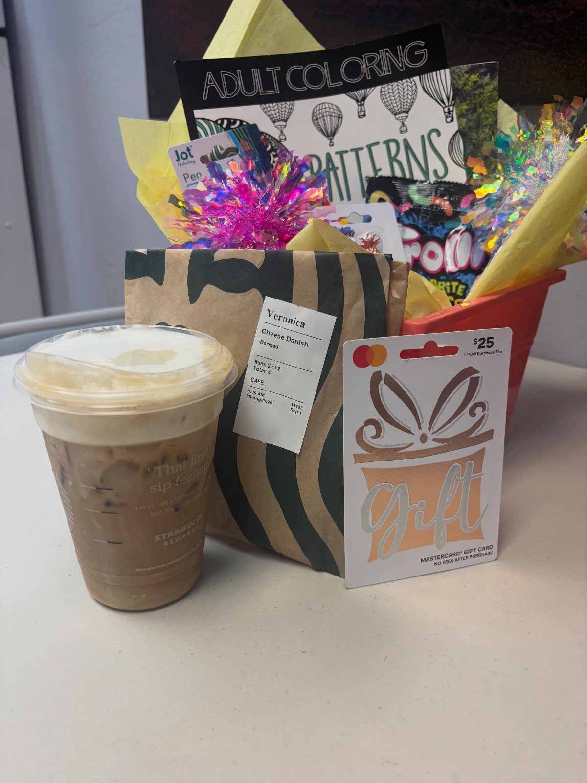 Iced coffee, gift card, and a red basket with adult coloring supplies.