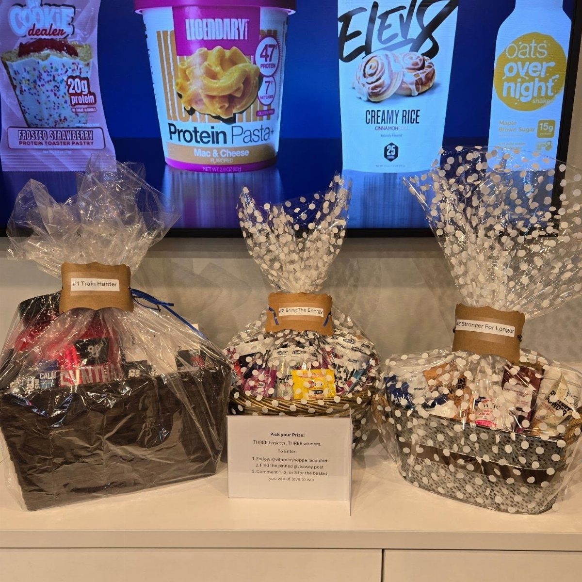 18 Gift Basket Prize Ideas for Raffles and Auctions 7 Three wrapped gift baskets with health products displayed in front of a digital screen.