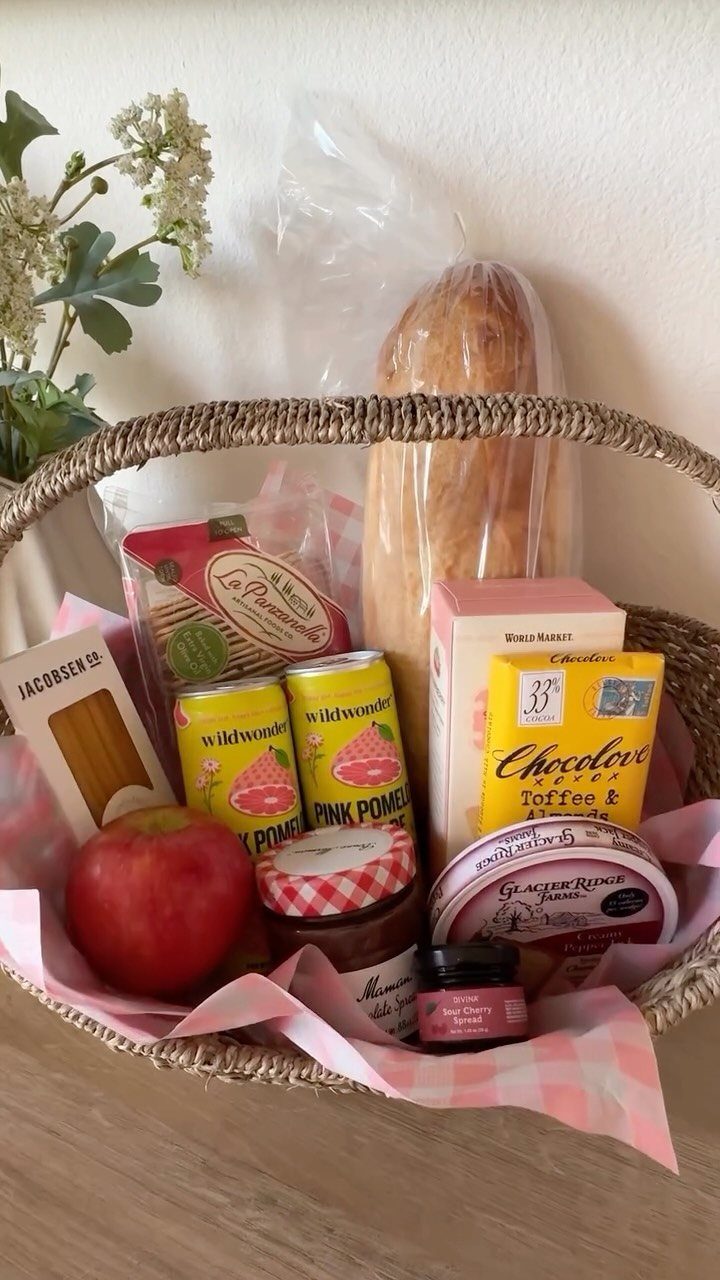 18 Gift Basket Prize Ideas for Raffles and Auctions 6 Woven gift basket filled with baguette, apple, jam, and gourmet treats on checkered fabric.