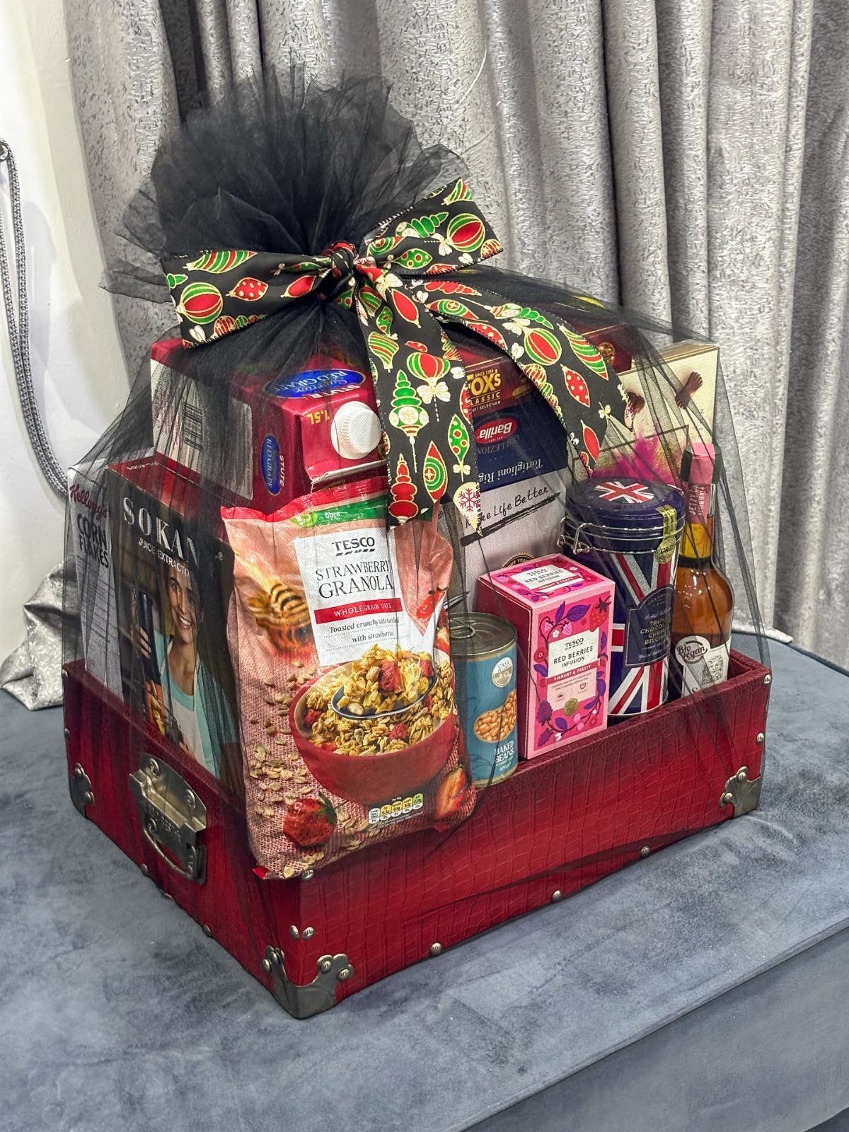 18 Gift Basket Prize Ideas for Raffles and Auctions 13 Red suitcase gift basket filled with treats, wrapped in black tulle and festive ribbon.