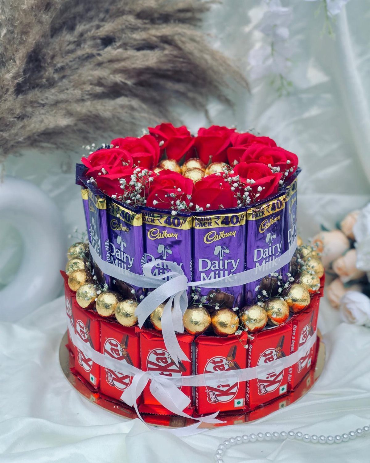 Gift Basket for Wedding: 5 Ideas for Couples and Guests 2 Two-tiered chocolate gift tower with red roses, gold chocolates, and white ribbons.