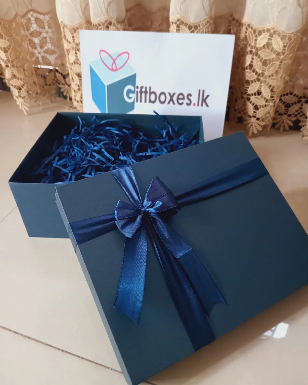 8 Gift Box Images: Red, Black, Pink, Blue and Clear 7 Dark blue gift box with a satin bow and matching shredded paper filler.