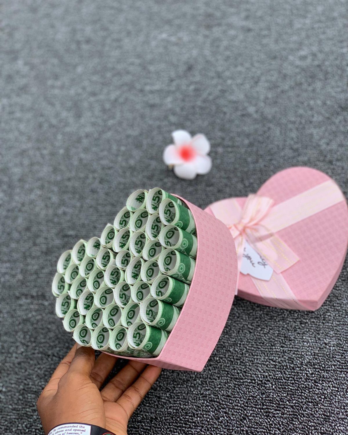 8 Gift Box Images: Red, Black, Pink, Blue and Clear 8 Pink heart-shaped gift box filled with rolled green banknotes on grey surface