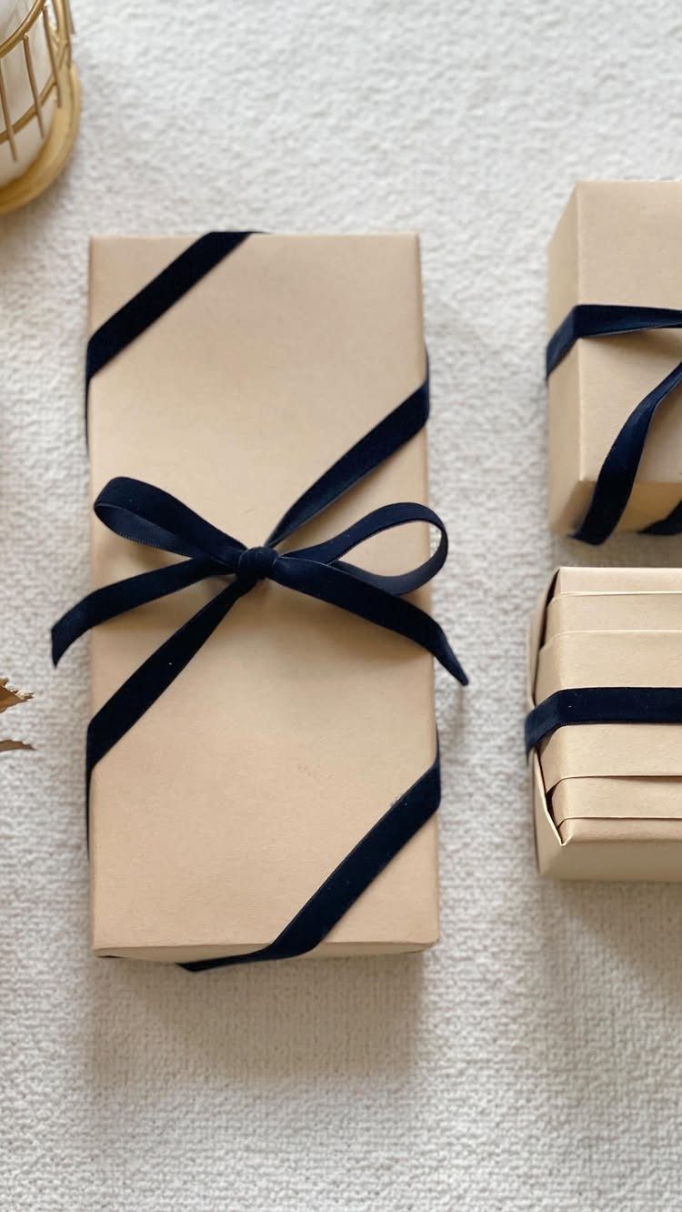Brown kraft paper gift boxes wrapped with dark navy blue velvet ribbon bows.