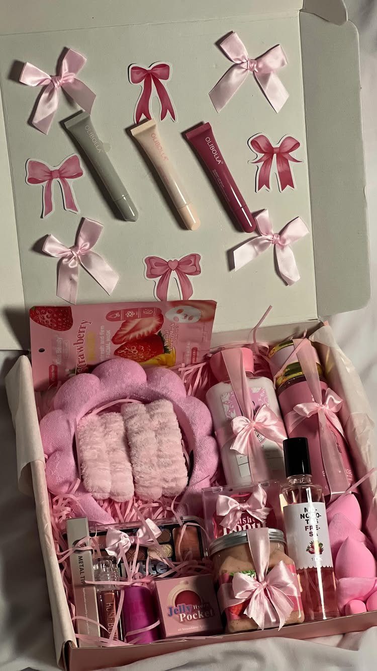 Open white gift box filled with pink beauty products and decorative bows.