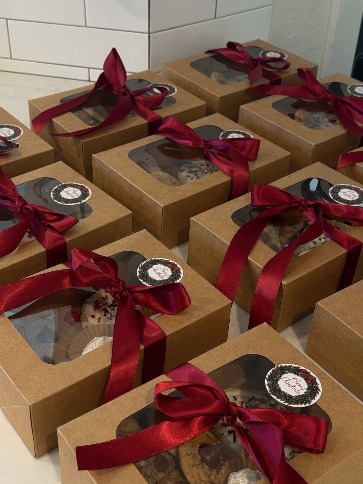 Brown cardboard gift boxes tied with red ribbons containing assorted homemade cookies.