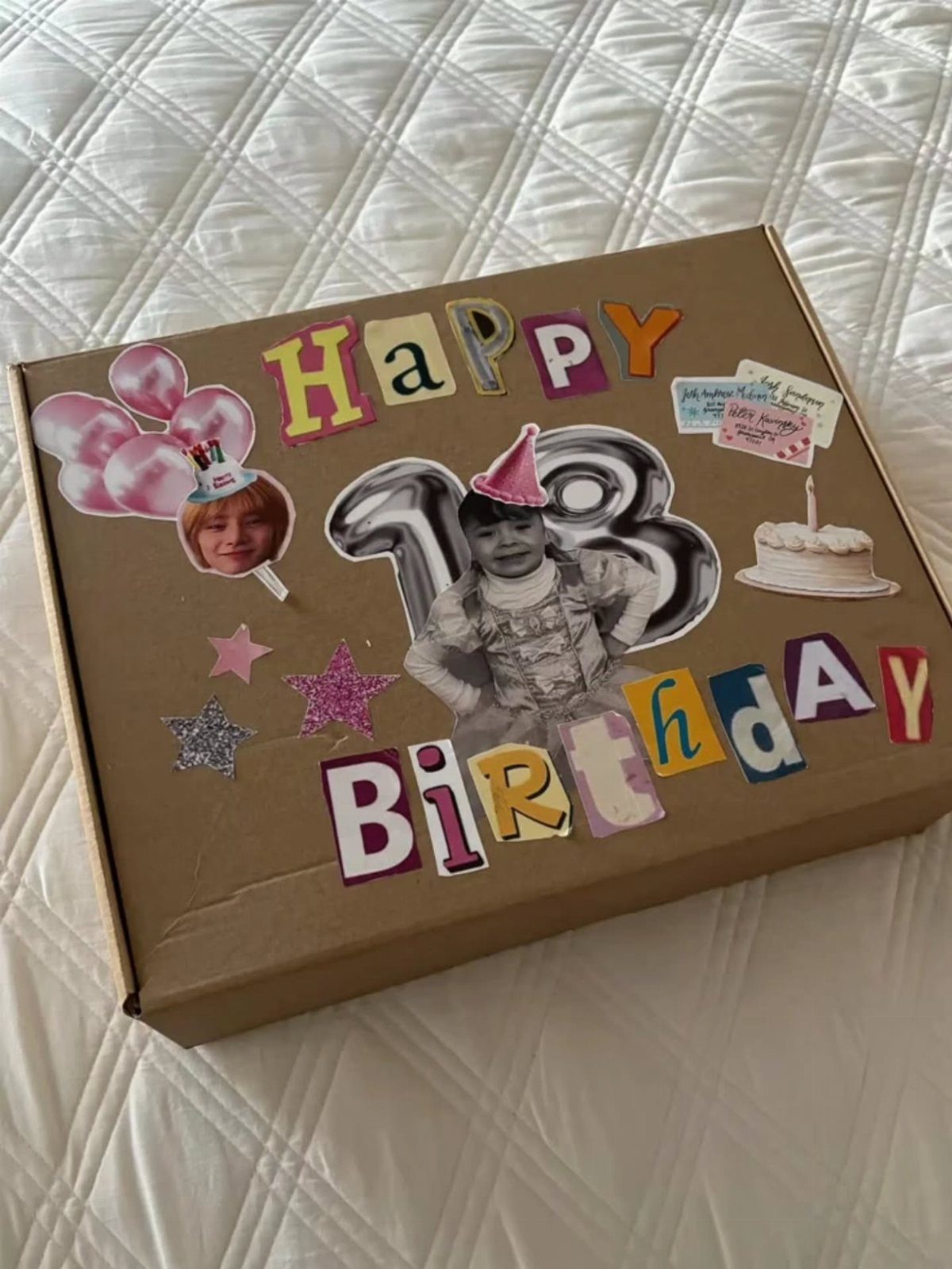 Brown cardboard birthday gift box decorated with photos, colorful letters, and balloons.