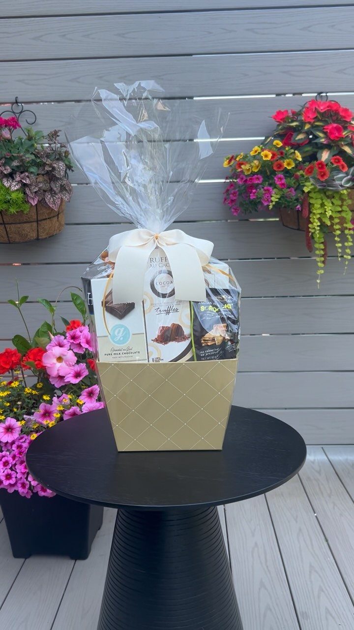 Gold gourmet food gift box wrapped in cellophane with a white ribbon bow.