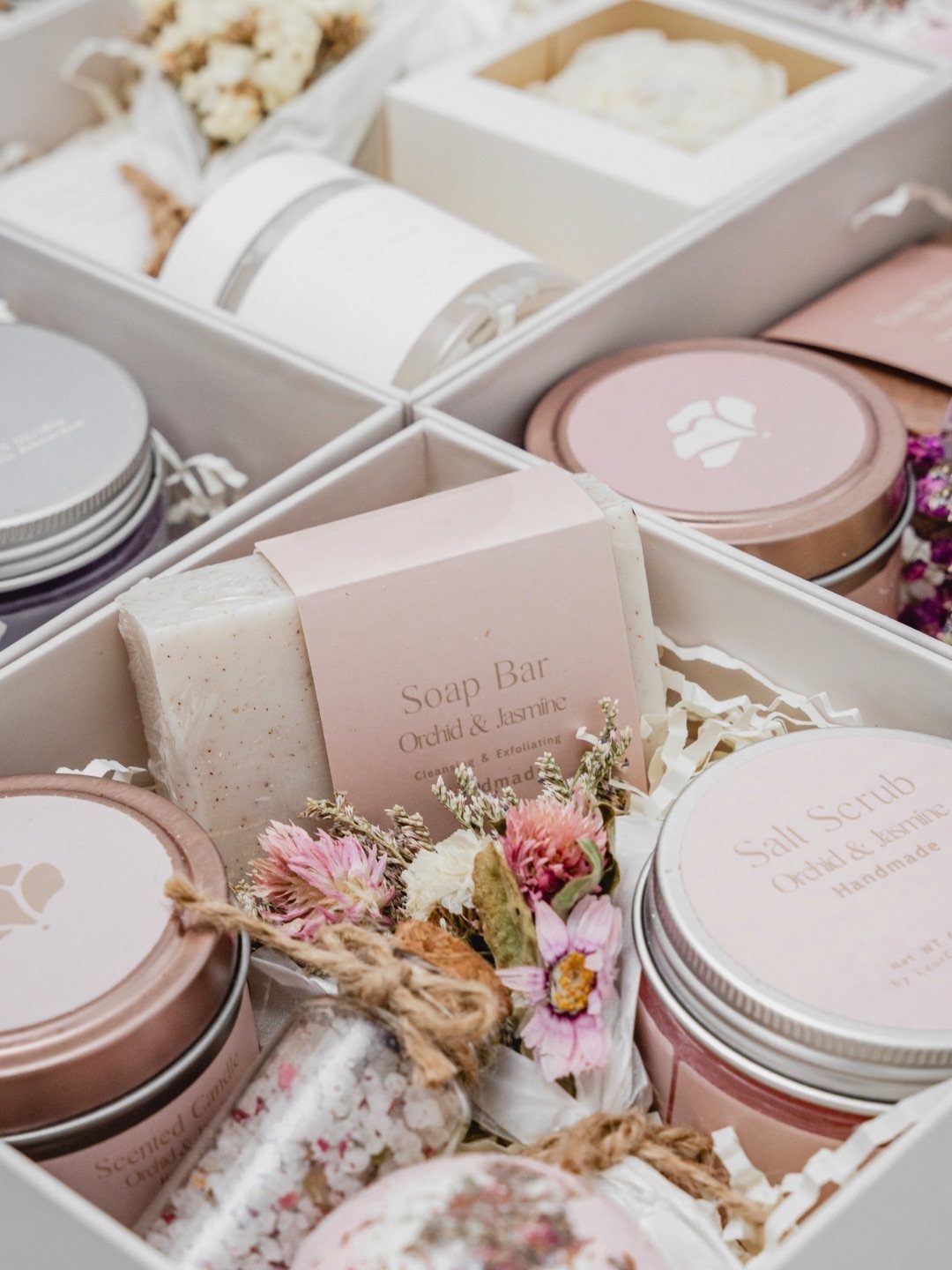 Spa gift boxes containing handmade soap, salt scrubs, and dried floral accents.