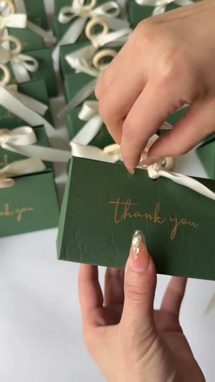 Small green gift boxes with gold thank you text and white ribbons.