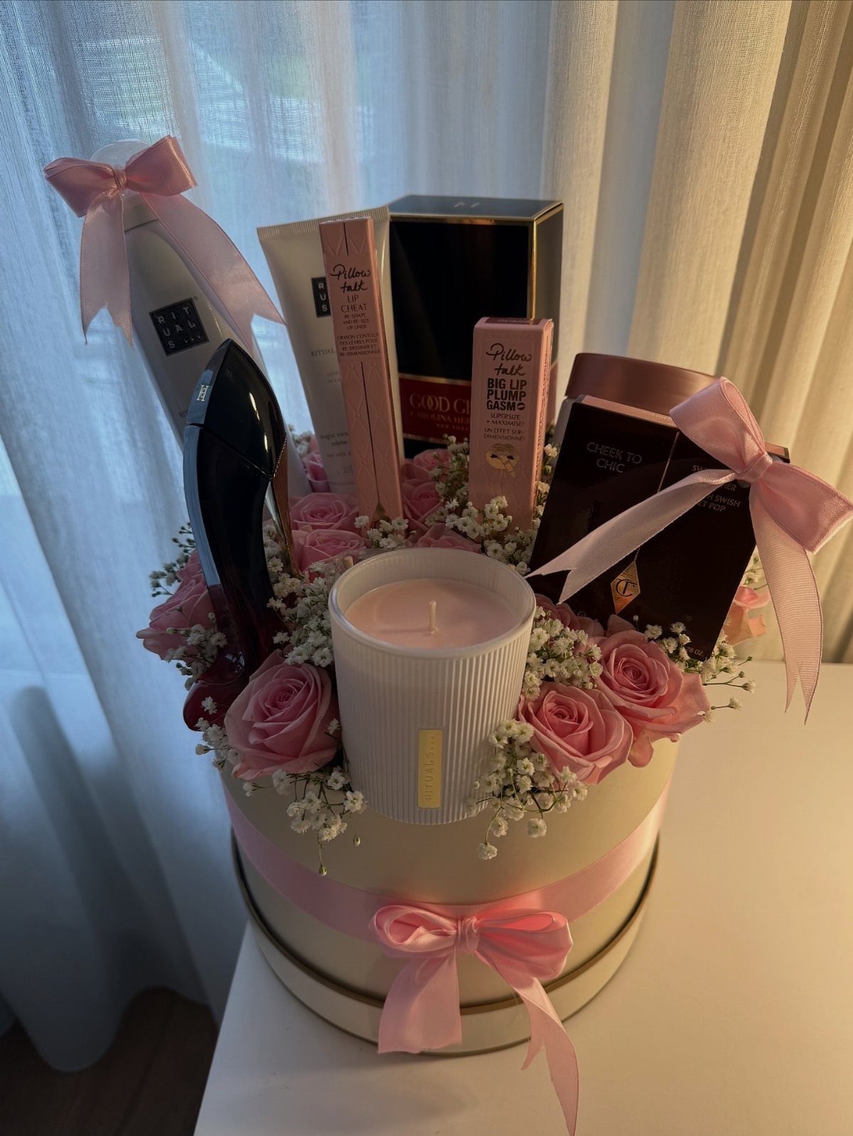Beauty gift box with pink roses, a white candle, and luxury cosmetics.