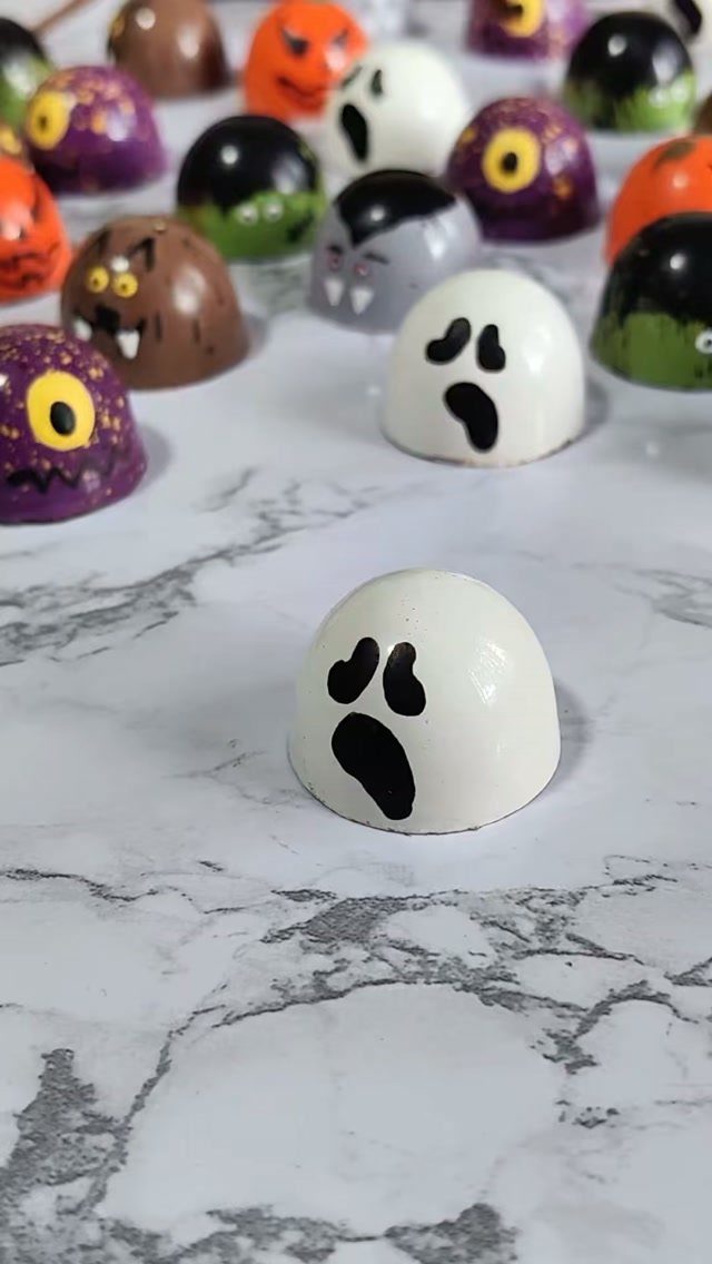 11 Gifts for Halloween Lovers: Candles, Socks and More 3 Halloween-themed gourmet chocolates shaped like ghosts and pumpkins on a marble surface