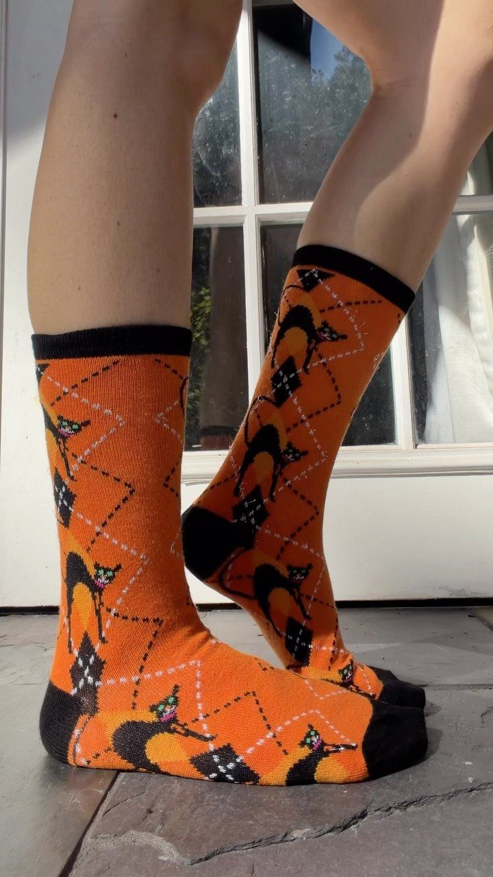 11 Gifts for Halloween Lovers: Candles, Socks and More 5 Orange Halloween socks with black cats worn on a person's feet.
