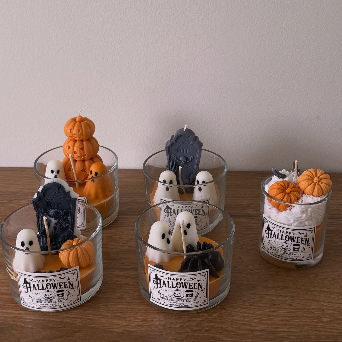 11 Gifts for Halloween Lovers: Candles, Socks and More 1 Halloween candles in glass jars with ghosts, pumpkins, and tombstones on wooden table