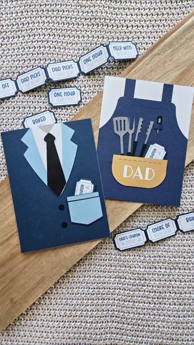 Handmade Father's Day cards and paper coupons on a wooden board and fabric.