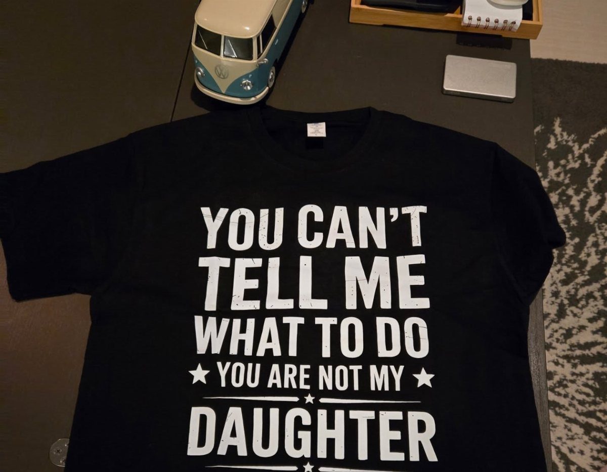 Black t-shirt with white text about a daughter laid on a dark table