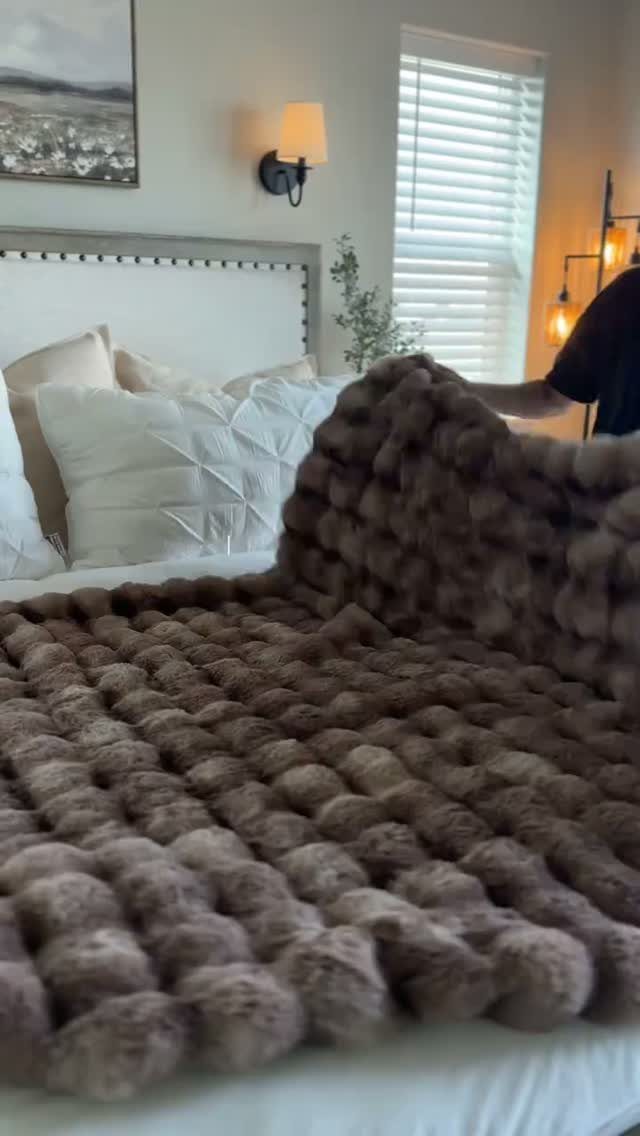 12 Good Gifts for Grandma She'll Actually Use and Treasure 8 Chunky knit brown blanket spread across a white bed in a bright bedroom