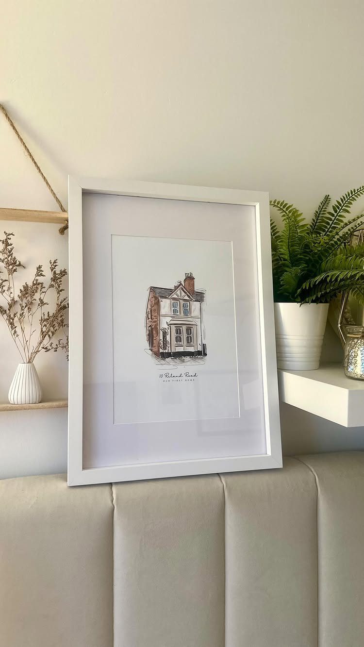 12 Good Gifts for Grandma She'll Actually Use and Treasure 10 Framed house illustration leaning on a headboard next to a potted green fern