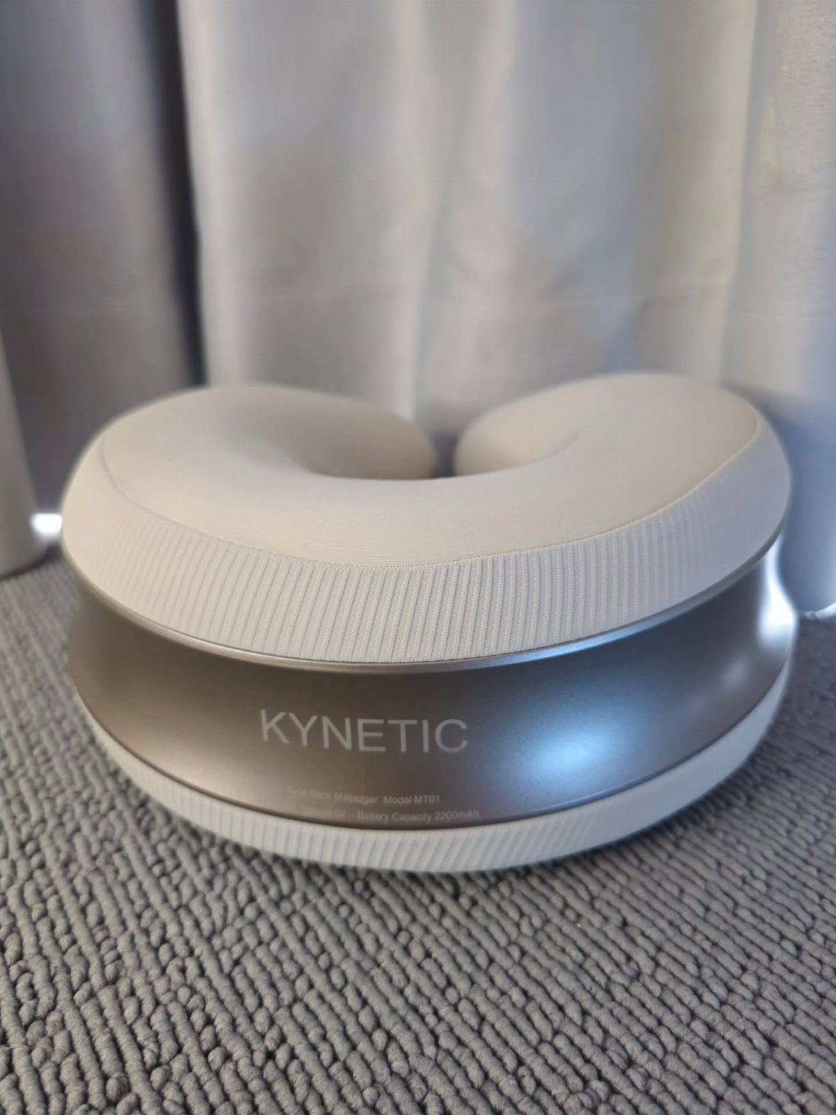 12 Good Gifts for Grandma She'll Actually Use and Treasure 9 Kynetic neck massager in white and silver on a grey textured surface.
