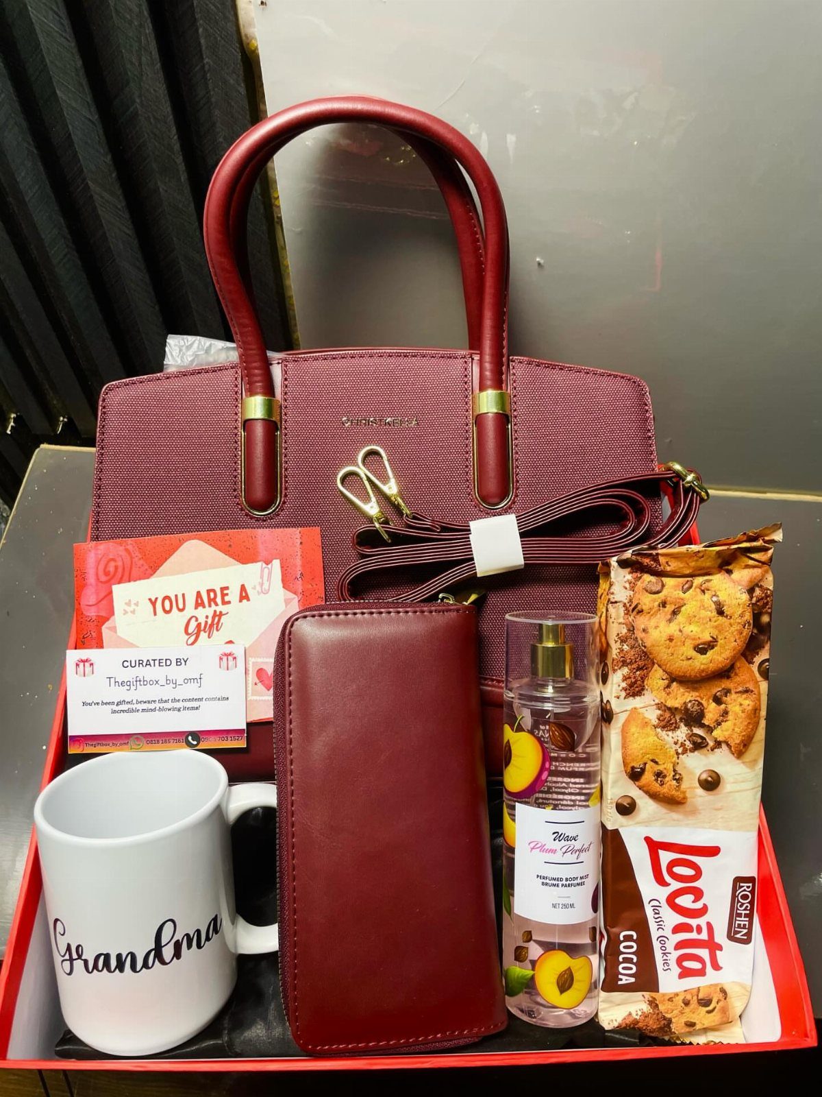 12 Good Gifts for Grandma She'll Actually Use and Treasure 6 Gift set for grandma featuring a burgundy handbag, wallet, and personalized white mug.