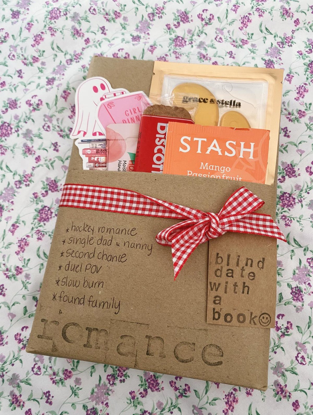 Brown paper envelope gift set with a book, snacks, and red checkered ribbon.