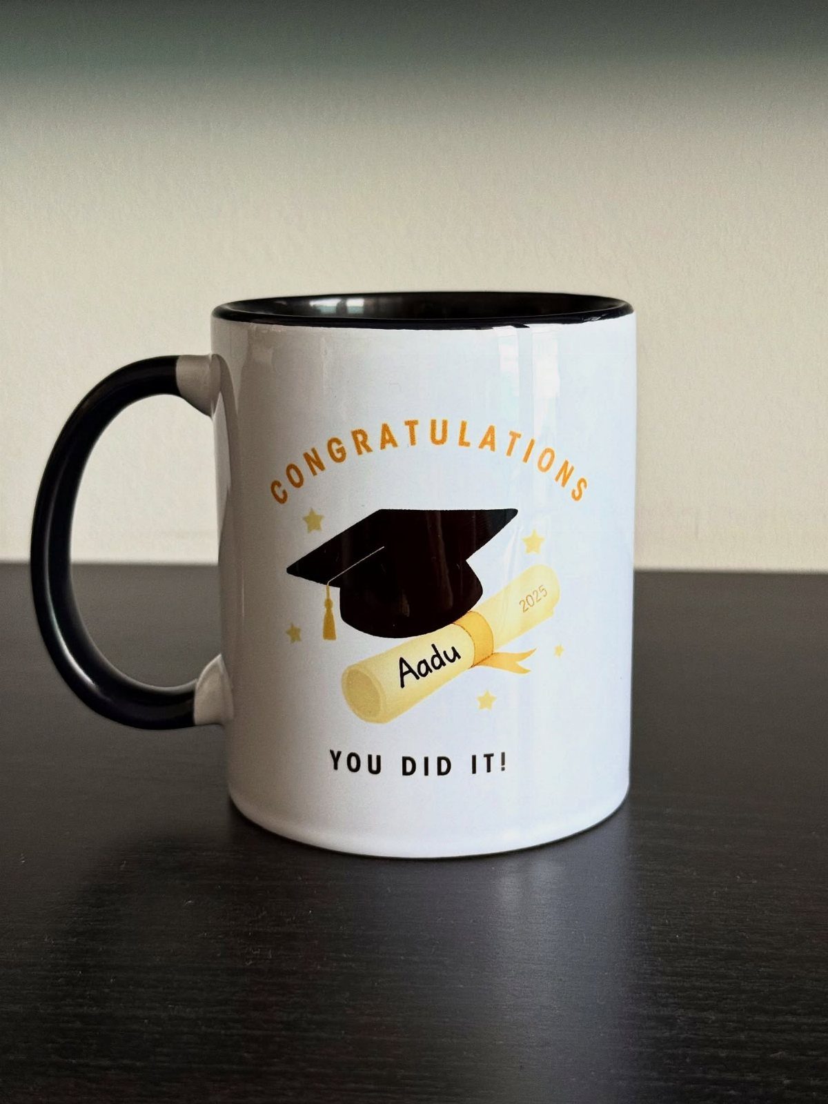 White graduation mug with a black cap and diploma on a dark table