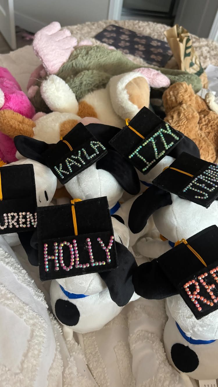 Plush bears wearing black graduation caps with personalized rhinestone names on top.