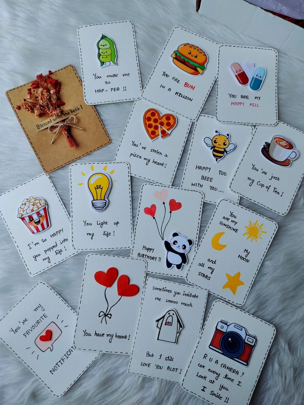 Handmade mini cards with cute illustrations and uplifting messages on a white fluffy surface.