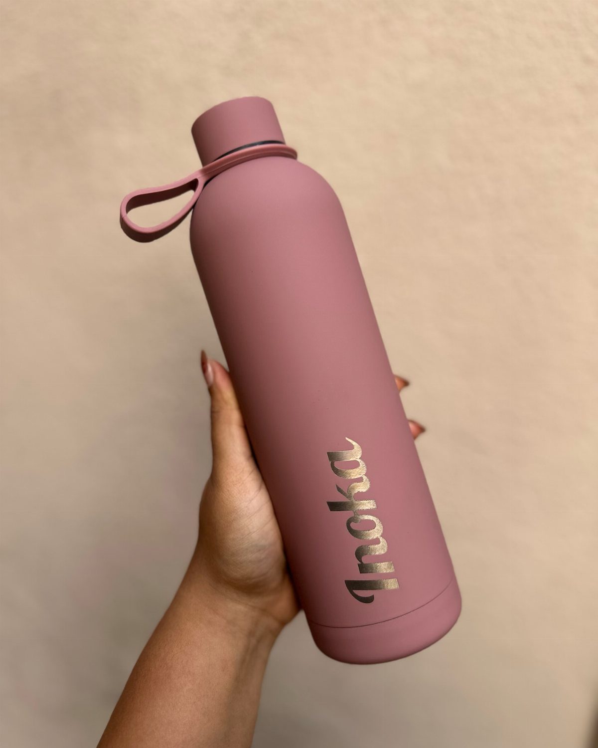 Dusty rose insulated water bottle with gold personalized cursive name held by hand