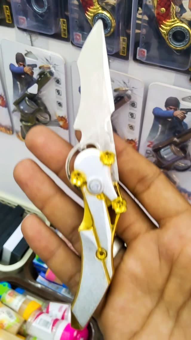White and gold folding pocket knife held in a person's hand