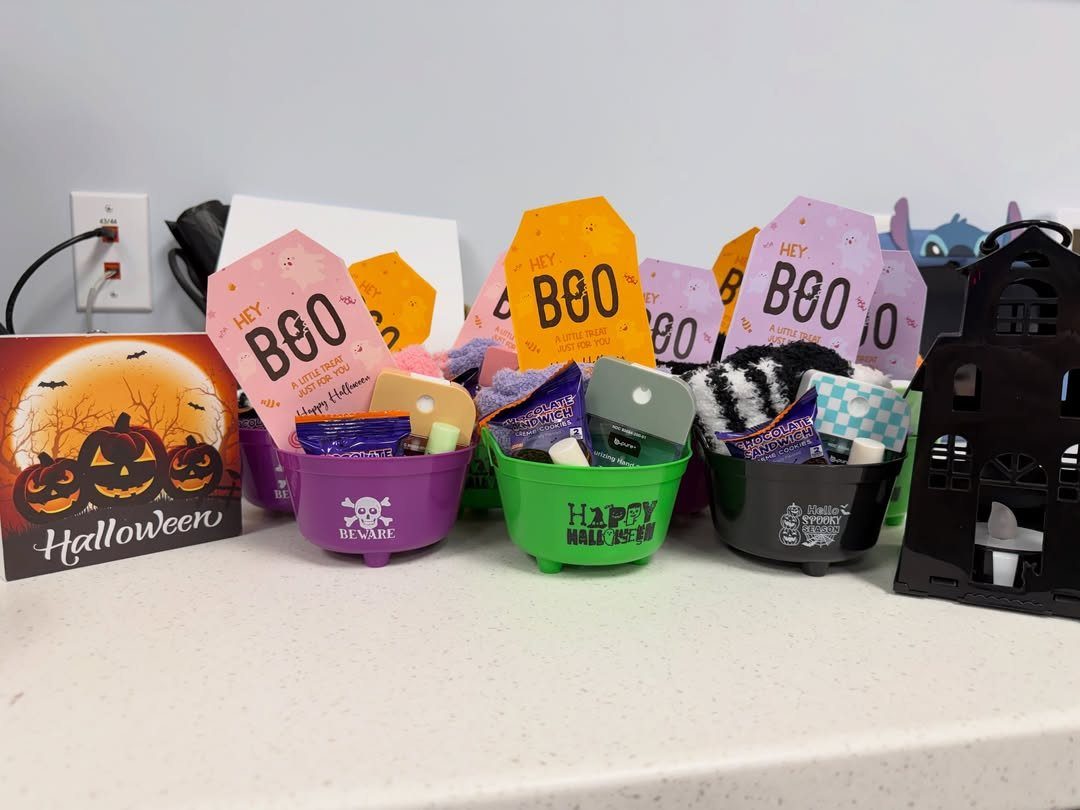 Colorful Halloween gift buckets filled with treats and tags on a white table.