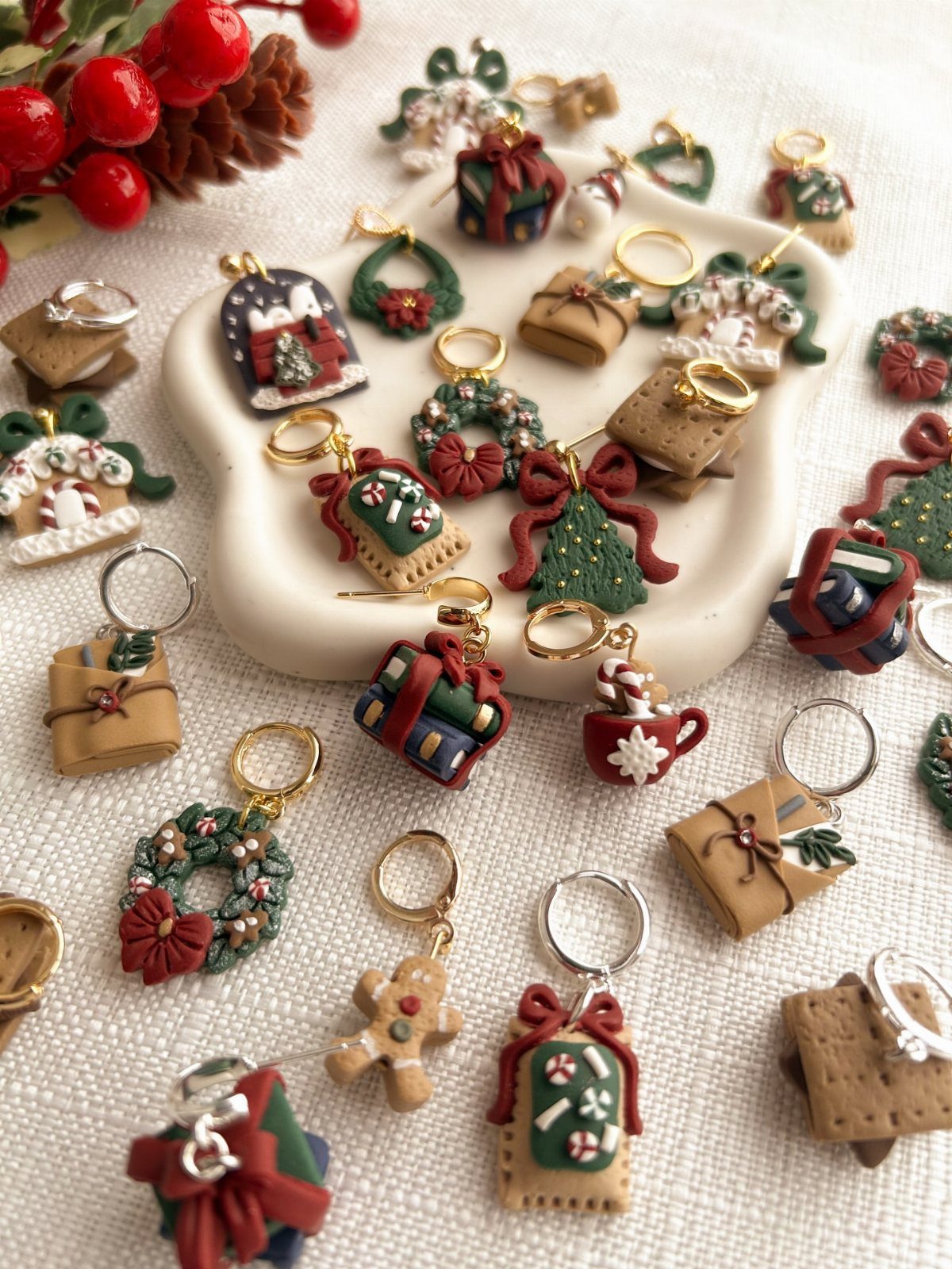 Handcrafted clay Christmas keychain charms in festive shapes scattered on white fabric.