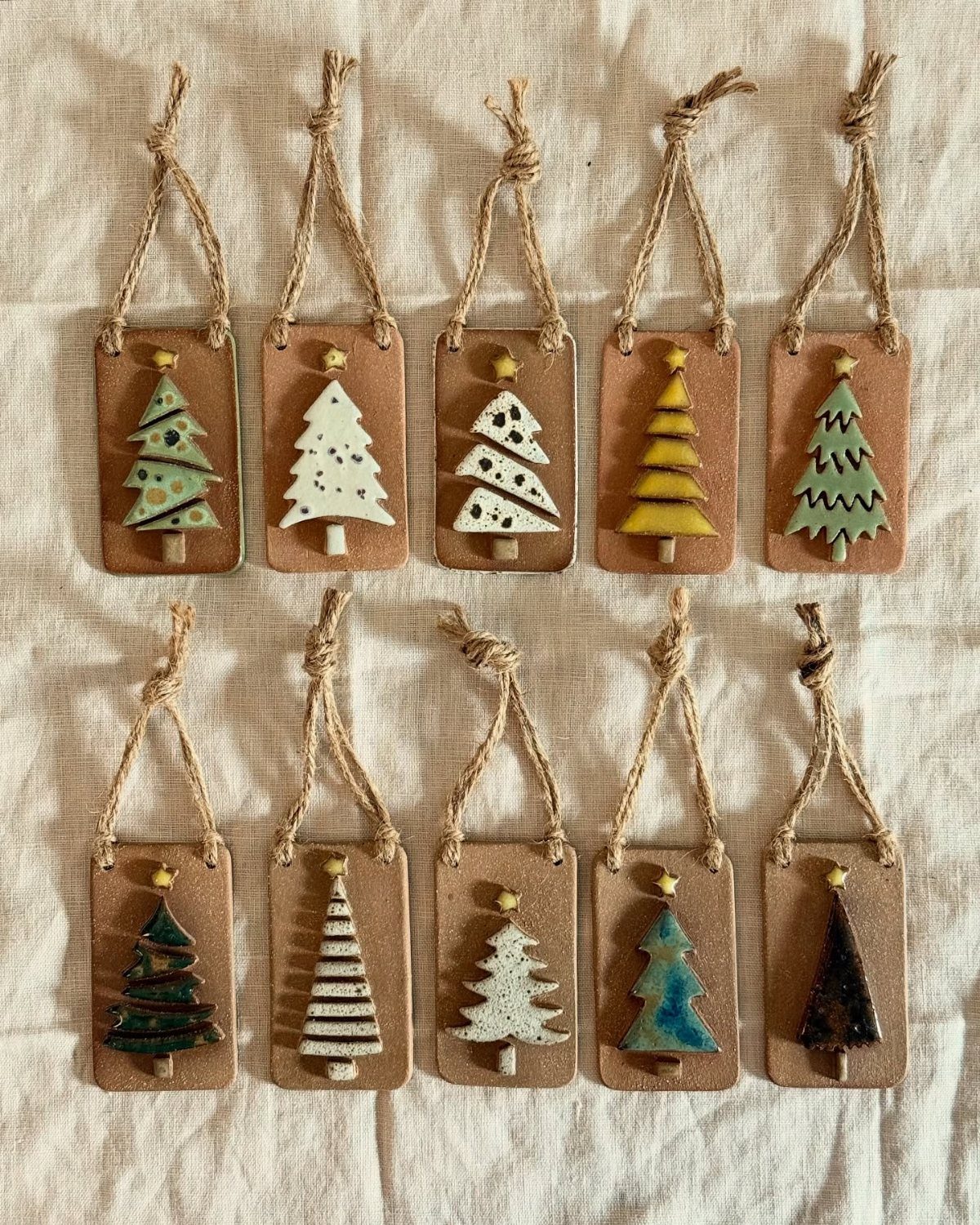 Handcrafted clay Christmas trees attached to brown leather tags with twine strings.