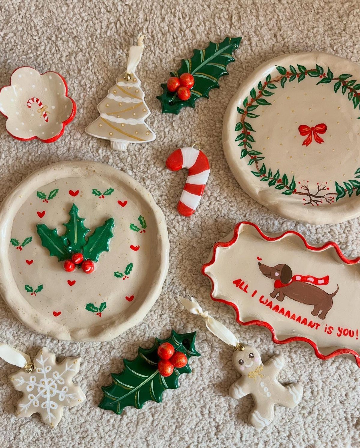Handcrafted clay trinket dishes and ornaments with festive Christmas designs on white fabric.