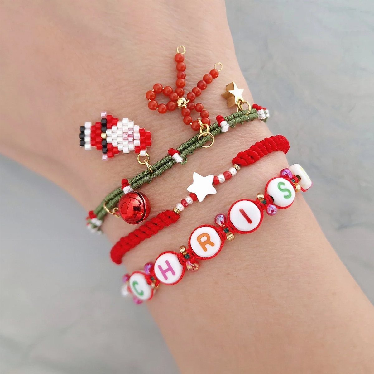 Four handcrafted beaded bracelets on a wrist, including one spelling the name Chris.